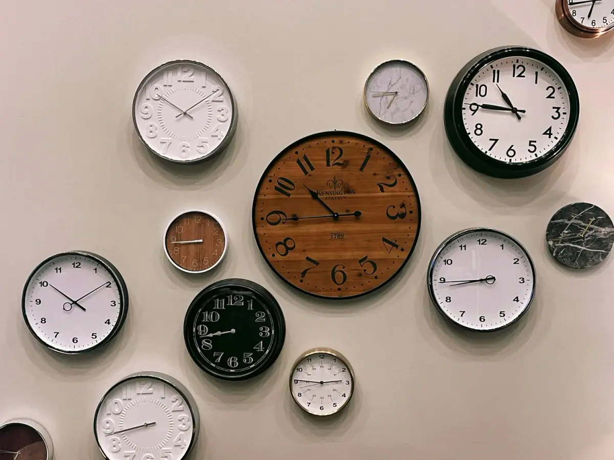 A wall covered with clocks of different sizes, styles and finishes, all showing different times.